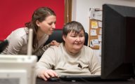 A person helping another do some work on a computer